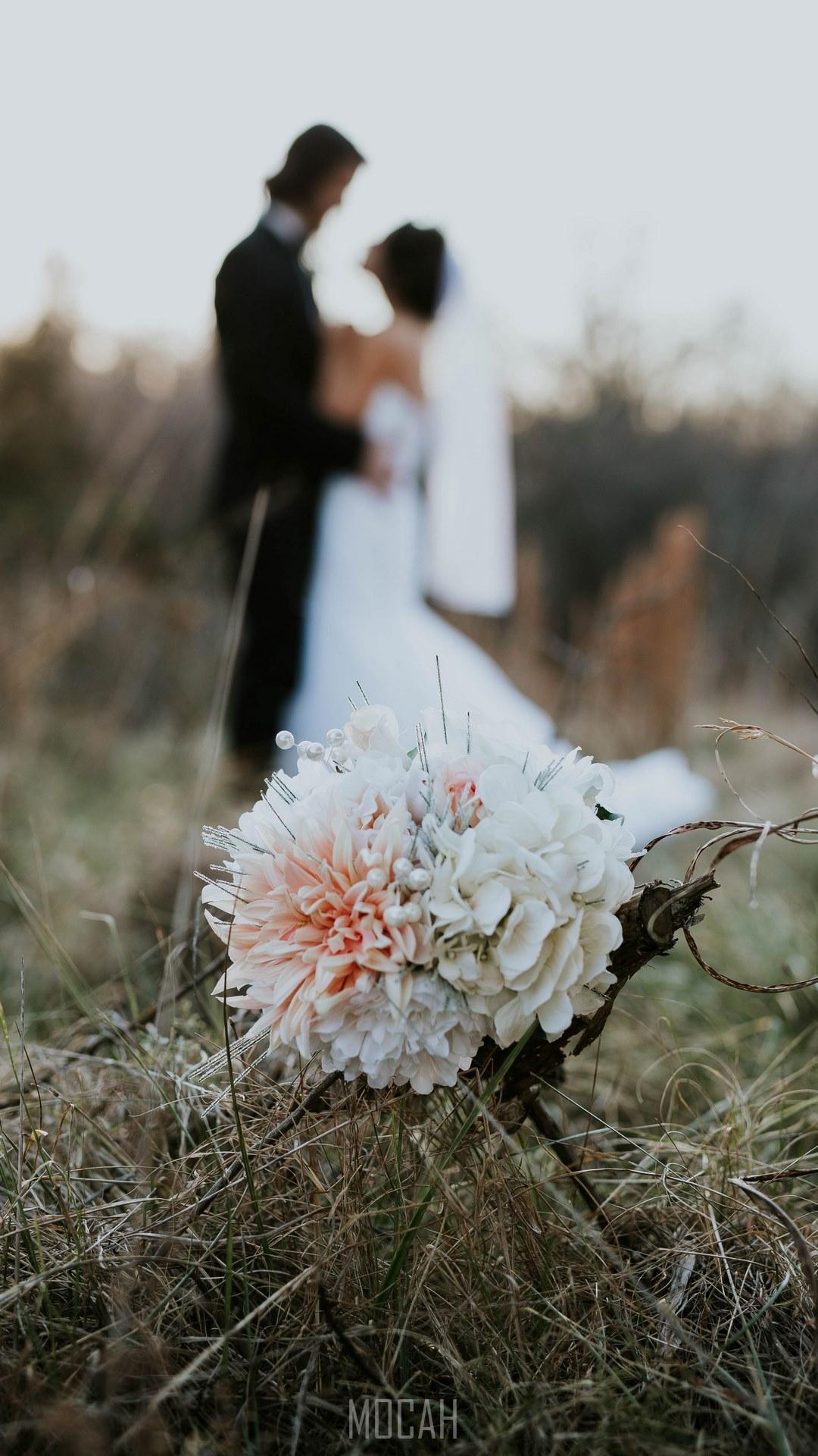 HD wallpaper, A Bouquet Sits In Tall Grass While A Married Couple Embraces In The Fuzzy Background, Samsung Galaxy J7 Prime Screensaver, 1080X1920, Wedding Evening